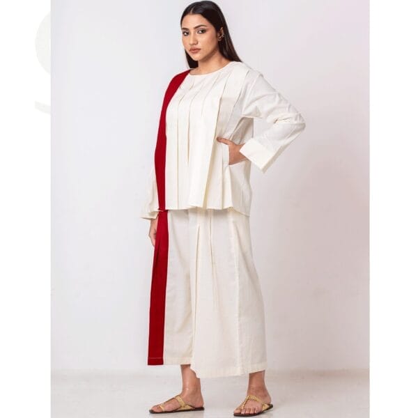 Step into effortless sophistication with this Minimalist Ivory Co-Ord Set with Red Stripe. The set features a pleated ivory top and wide-leg trousers, crafted from soft, eco-friendly fabric for ultimate comfort. Its bold red stripe detailing adds a touch of modern elegance, making it a versatile piece for both casual outings and refined occasions. Pair it with statement jewelry or minimalist footwear to complete the look.